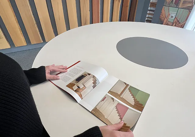 Treppenmagazin von Göhler wird von einer Frau in den Händen gehalten, über einem runden Tisch.