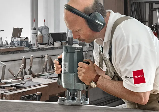 Mann mit Oberfräse bearbeitet Holz