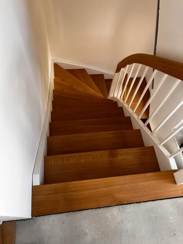 Einfache, rustikale Treppe aus Holz mit weißen Geländerstreben, Viertelgewendelt.