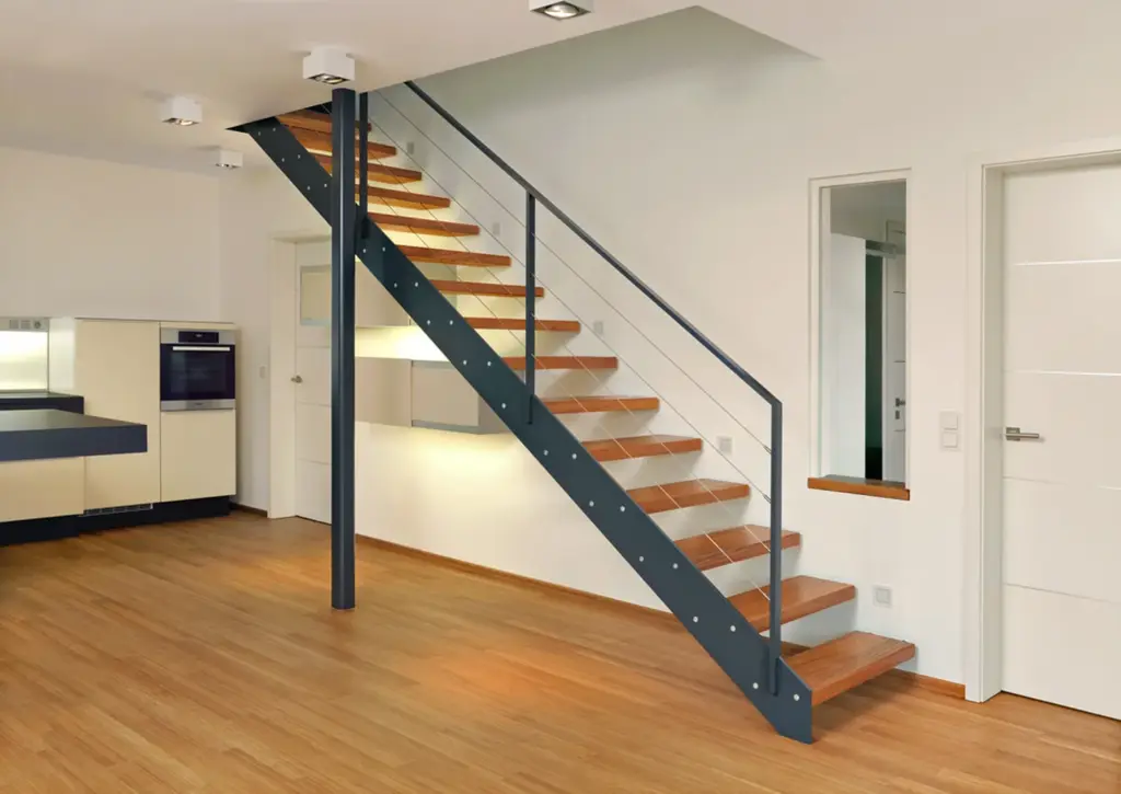 Ein modernes Interieur mit Holzböden, einer Treppe mit Holzstufen und einem schwarzen Metallgeländer, weißen Wänden und einer minimalistischen Küche im Hintergrund. Auf der rechten Seite sind zwei weiße Türen zu sehen.