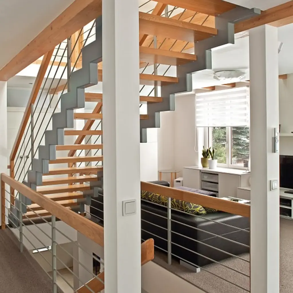 Modernes Interieur mit einer offenen Holztreppe, Metallgeländer und einem Wohnbereich mit schwarzem Sofa, Jalousien und neutralen Wänden. Durch die großen Fenster wird der Raum von natürlichem Licht durchflutet.