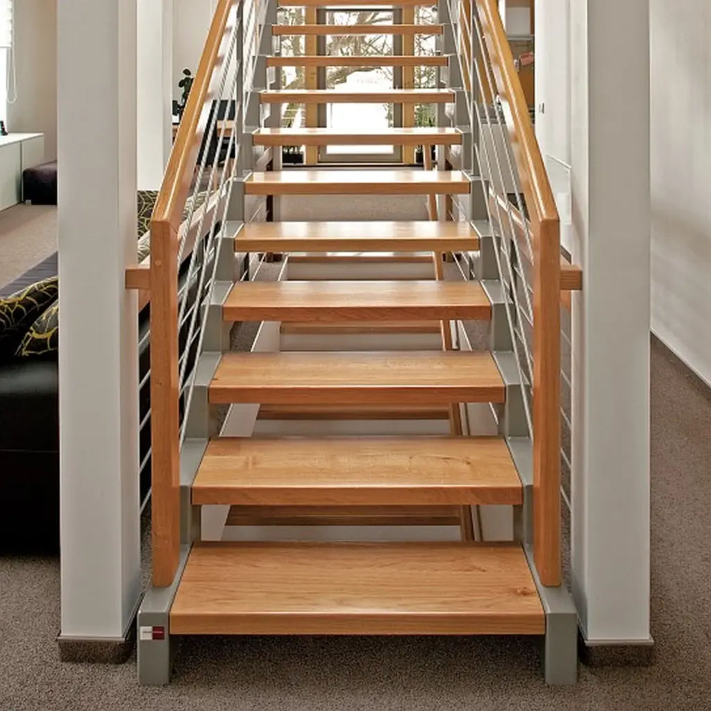 Moderne Innentreppe mit Holzstufen, Metallstützen und Holzhandläufen, die zwischen weißen Wänden in einem mit Teppich ausgelegten Raum nach oben führt.